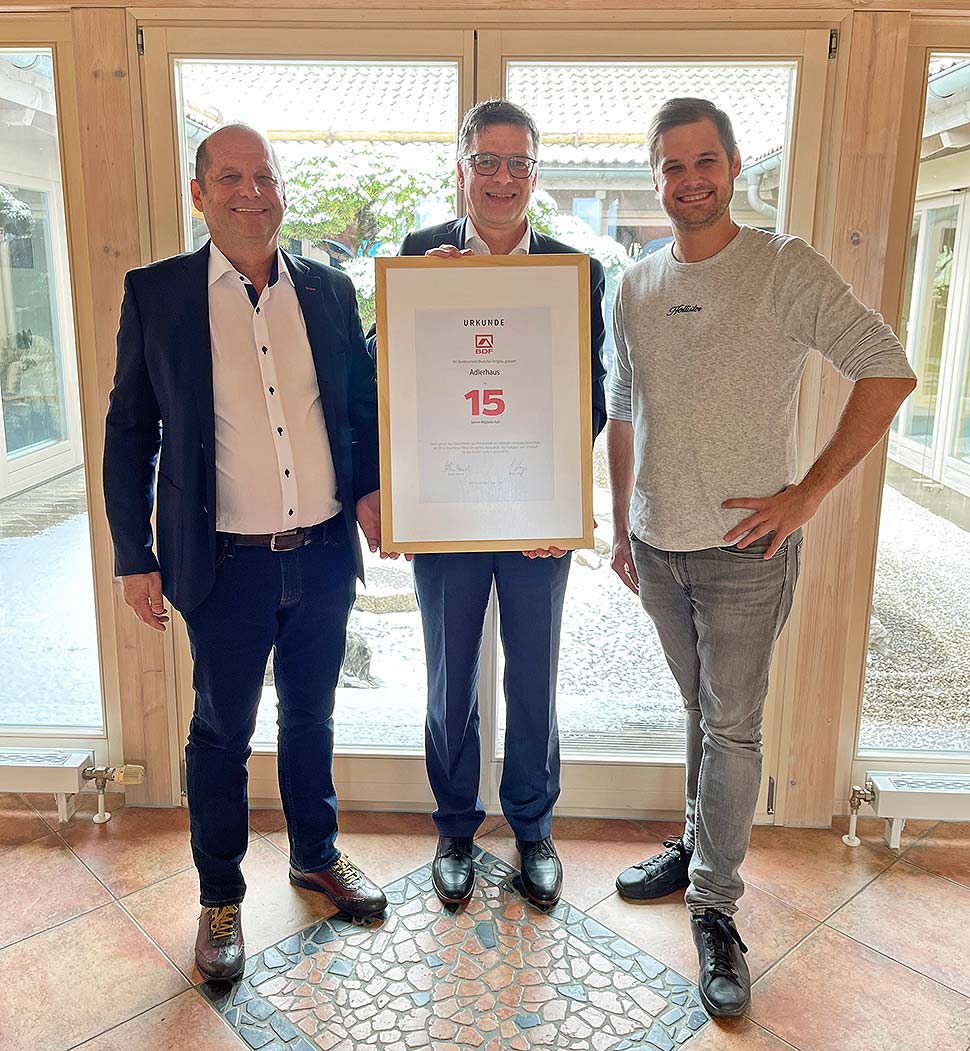 BDF-Geschäftsführer Georg Lange (m.) überreichte eine Urkunde an Marco Adler (l.) und Felix Adler (r.) vom Familienunternehmen Adlerhaus. Foto: Adlerhaus