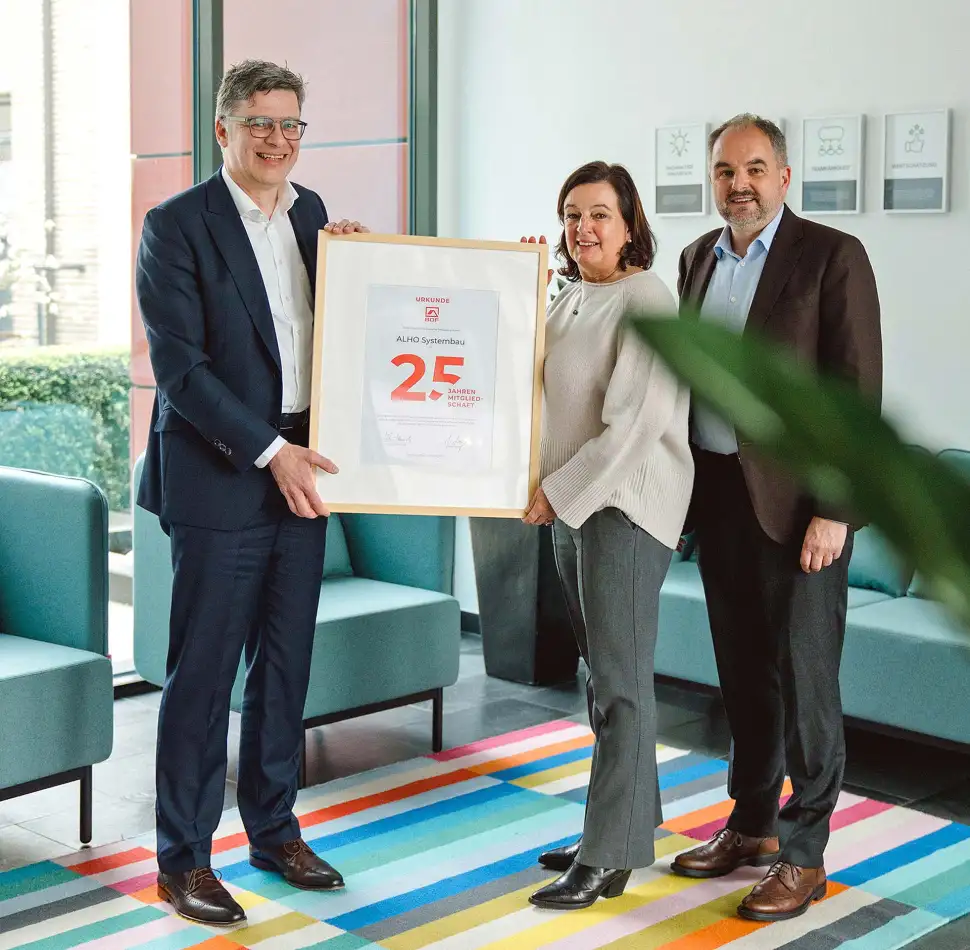 Im Namen der ALHO-Inhaberfamilie nahmen Silvia Matschke (m.), Geschäftsführung FAGSI Vertriebs- und Vermietungs-GmbH, und Achim Holschbach (r.), Geschäftsführung ALHO Holding GmbH, jetzt die Jubiläumsurkunde von BDF-Geschäftsführer Georg Lange (l.) entgegen. Foto: ALHO Systembau