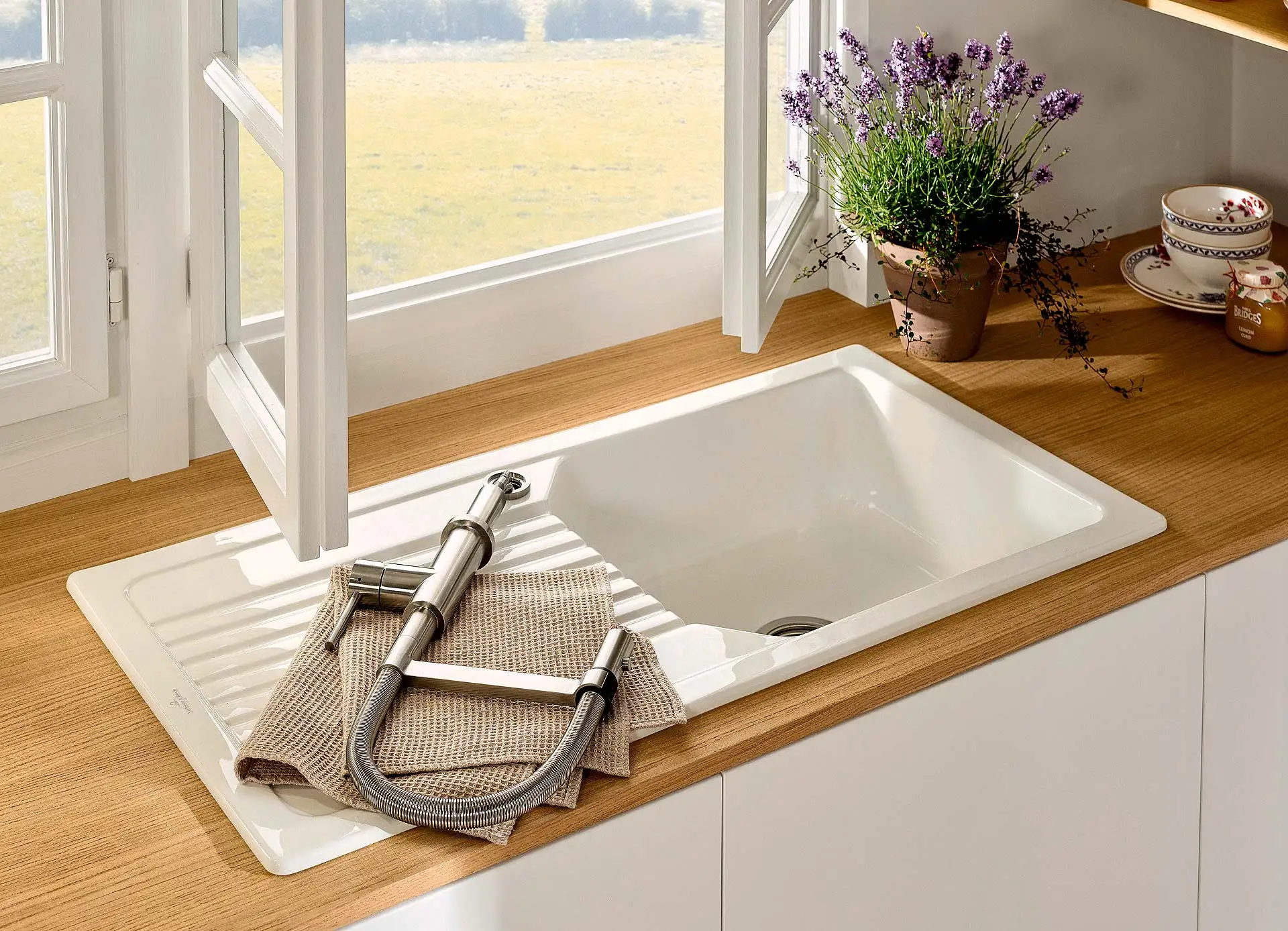 Ein Spülenplatz mit Aussicht, aber die Armatur stört beim Fensteröffnen? Die Lösung findet sich in einer neu entwickelten Vorfensterarmatur. Denn die Edelstahlarmatur lässt sich einfach aus ihrer Halterung ziehen, ablegen und wieder aufstecken – dadurch ist der Weg für das Fenster immer frei. (Foto: HLC/Villeroy & Boch)